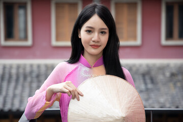 face portrait of happy smiling girl; portrait of positive relaxed happy smiling asian woman smiles in city outdoor; young adult Vietnamese asian woman model in traditional Vietnamese Ao Dai dress