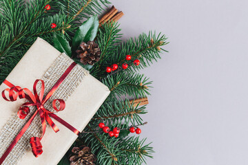 Craft gift box with spruce branch and red berries on a grey background. Holiday eco-friendly concept.