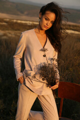 Wall Mural - beautiful woman with dark hair in elegant clothes posing in autumn field