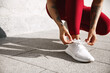 © Liubov Levytska - Cropped view of female runner tie shoelaces on outdoor jogging exercises. Sportswoman tying shoes before cardio exercises on street