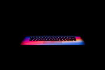 Canvas Print - Colorful light coming out of a laptop screen in the darkness