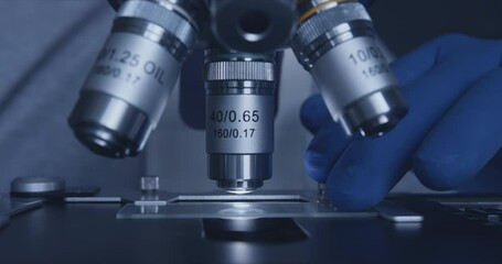 Wall Mural - close-up shot of sample slide and microscope with metal lens at laboratory.