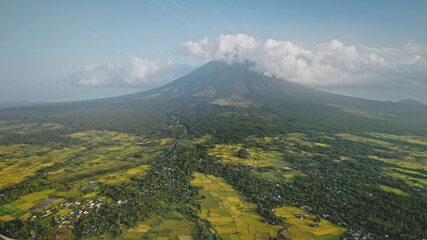 Wall Mural - Mayon volcano erupts at Philippines countryside aerial. Tropic green forest plants and grasses at picturesque nobody nature landscape. Legazpi town at mountain hillside valley at cinematic drone shot