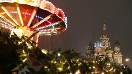 Wall Mural - Big carousel on the Red Square in Moscow.Christmas market in the city.People have fun together on holidays.Fur branches and St. Basil's Cathedral background