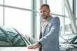 © pressmaster - Contemporary mature man in smart casualwear keeping hand on front of new car
