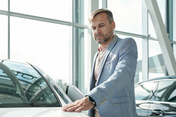 Poster - Contemporary mature man in smart casualwear keeping hand on front of new car