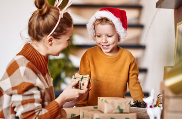 Sticker - Cheerful family mother and son wrapping gifts together for Christmas .