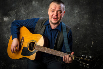 Wall Mural - Mature musician plays acoustic guitar emotional studio portrait.