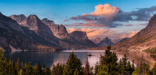 Beautiful Panoramic View Of A Glacier Lake With American Rocky Mountain Landscape In The Background. Dramatic Colorful Sunrise Sky. Taken In Glacier National Park, Montana, United States.