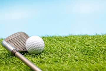 Wall Mural - Golf ball with iron are on green grass on blue sky background