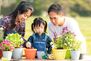 Family child girl helping parent care plant flower in garden. Young people mom  father and daughter gardening outdoor sunny  nature background. Happy and enjoy in spring and summer day.