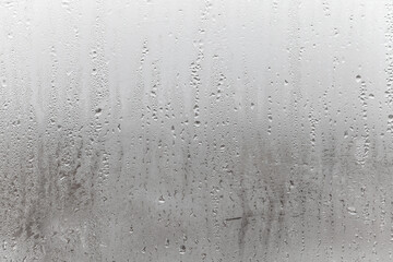 Natural drops of water flow down the glass, high humidity in the room, condensation on the glass window. Neutral colors. Excellent background with condensation drops texture