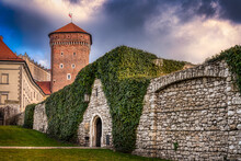 Senator's Bastion With The Clambering Plant Covered Stone Wall Of The Wawel Castle In The Center Of Krakow, Poland Below A Dark And Cloudy Sky