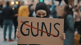 Fototapeta Na ścianę - No guns. Young woman with face mask holding banner against gun violence. Demonstration and revolution concept. High quality photo