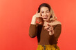 © khosrork - Portrait of young pretty woman with blonde hair smiling, showing a gesture of a phone and ask you for call her, pointing finger at the camera. Indoor studio shot isolated on red background.