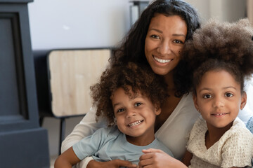 Our favorite teacher. Portrait of happy friendly african family millennial mother and two diverse children, talented black female tutor babysitter looking at camera posing with beloved pupils wards