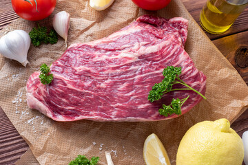 Wall Mural - a piece of marbled beef lies on parchment surrounded by herbs, garlic, salt. Top view, flat lay. food composition