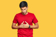 © Krakenimages.com - Young handsome man wearing casual red tshirt with hand on stomach because indigestion, painful illness feeling unwell. ache concept.