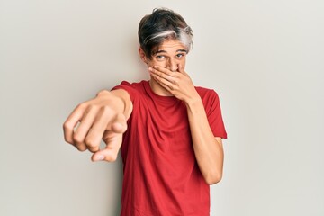 Poster - Young hispanic man wearing casual clothes laughing at you, pointing finger to the camera with hand over mouth, shame expression