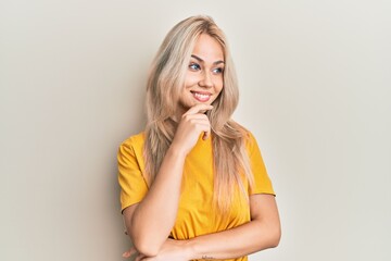 Sticker - Beautiful caucasian blonde girl wearing casual tshirt with hand on chin thinking about question, pensive expression. smiling with thoughtful face. doubt concept.