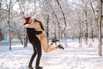 Wall Mural - Loving couple hugging and kissing in snow forest. Enjoying time together. The concept of youth, love and lifestyle. Winter holidays.