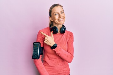 Sticker - Beautiful caucasian woman wearing sportswear and arm band cheerful with a smile of face pointing with hand and finger up to the side with happy and natural expression on face