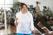 © DenisProduction.com - Senior woman holding bottle of water at gym. Happy elderly woman looking at camera at sport club. People, sport and healthy lifestyle.