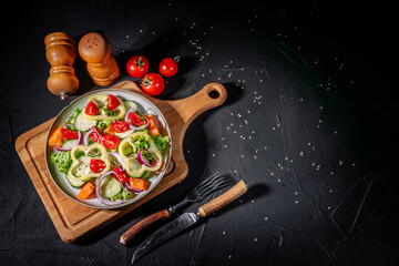 Wall Mural - Healthy vegetable salad of fresh tomato, green leaves mix and vegetables. Top view on dark bacground. Diet menu