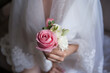 Bride holding wedding boutonniere in hand. Bunch of flowers for groom in wedding day. Little bouquet of roses
