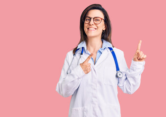 Wall Mural - Young beautiful woman wearing doctor stethoscope and glasses smiling and looking at the camera pointing with two hands and fingers to the side.