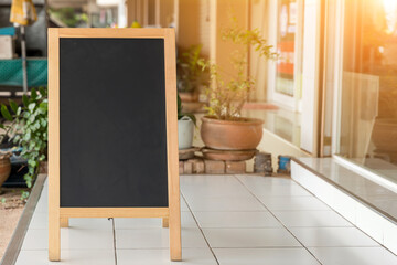 Wall Mural - Wooden rustic blackboard in front of restaurant entrance. Mock up Menu Blank Blackboard sign stand Shop Cafe Restaurant. Street Magnetic Sidewalk Chalkboard.