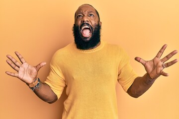 Young african american man wearing casual clothes crazy and mad shouting and yelling with aggressive expression and arms raised. frustration concept.