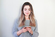 © Hazal - Young woman over isolated gray background sending a message with the mobile