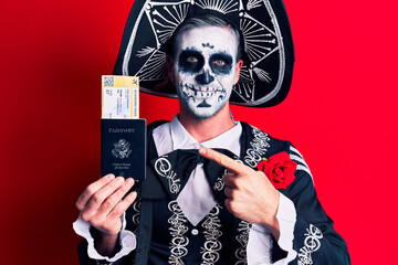 Wall Mural - Young man wearing mexican day of the dead costume holding united states passport and boarding pass smiling happy pointing with hand and finger