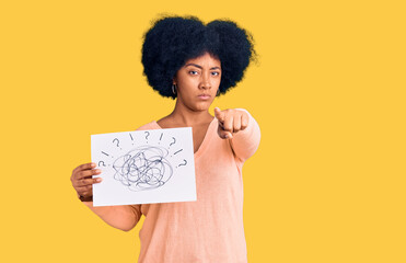 Sticker - Young african american girl holding scribble draw pointing with finger to the camera and to you, confident gesture looking serious