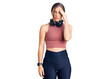 © Krakenimages.com - Beautiful caucasian young woman wearing gym clothes and using headphones worried and stressed about a problem with hand on forehead, nervous and anxious for crisis