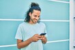 © Krakenimages.com - Young hispanic man smiling happy using smartphone leaning on the wall