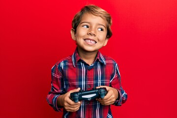 Wall Mural - Adorable latin kid playing video game holding controller smiling with a happy and cool smile on face. showing teeth.