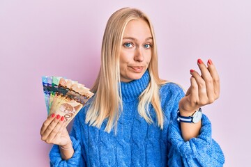 Canvas Print - Young blonde girl holding canadian dollars doing italian gesture with hand and fingers confident expression