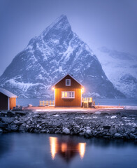 Wall Mural - alone rorbu on sea coast and snow covered mountain at night in winter. lofoten islands, norway. land