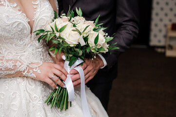 bride and groom holding a bouquet of white roses