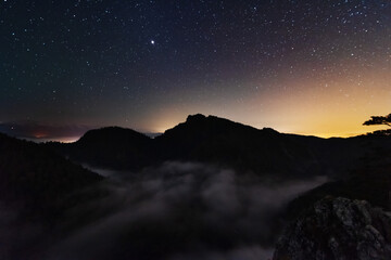 Wall Mural - A beautiful starry night in the mountains on top with beautiful scenery and fog.	