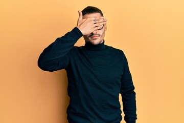 Poster - Handsome man with tattoos wearing turtleneck sweater and glasses covering eyes with hand, looking serious and sad. sightless, hiding and rejection concept