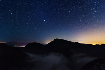 Wall Mural - A beautiful starry night in the mountains on top with beautiful scenery and fog.	