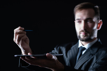 Poster - hands of a man with a tablet and a stylus close-up. blurry face of a man and an electronic tablet. g