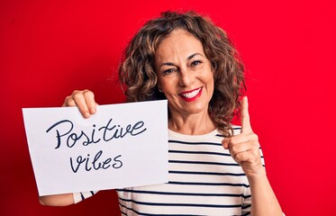 Sticker - Middle age brunette woman asking for good attitude holding paper with positive vibes message smiling with an idea or question pointing finger with happy face, number one