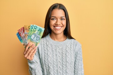 Canvas Print - Beautiful hispanic woman holding australian dollars looking positive and happy standing and smiling with a confident smile showing teeth