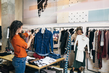 Wall Mural - Beautiful young women trying elegant clothes in expensive boutique or store.