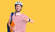 © Krakenimages.com - Young hispanic man wearing student backpack and bike helmet holding binder pointing finger to one self smiling happy and proud