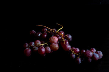 Red grapes, large bunch of fruits, fresh and tasty simple food on a dark background in a fancy minimal composition